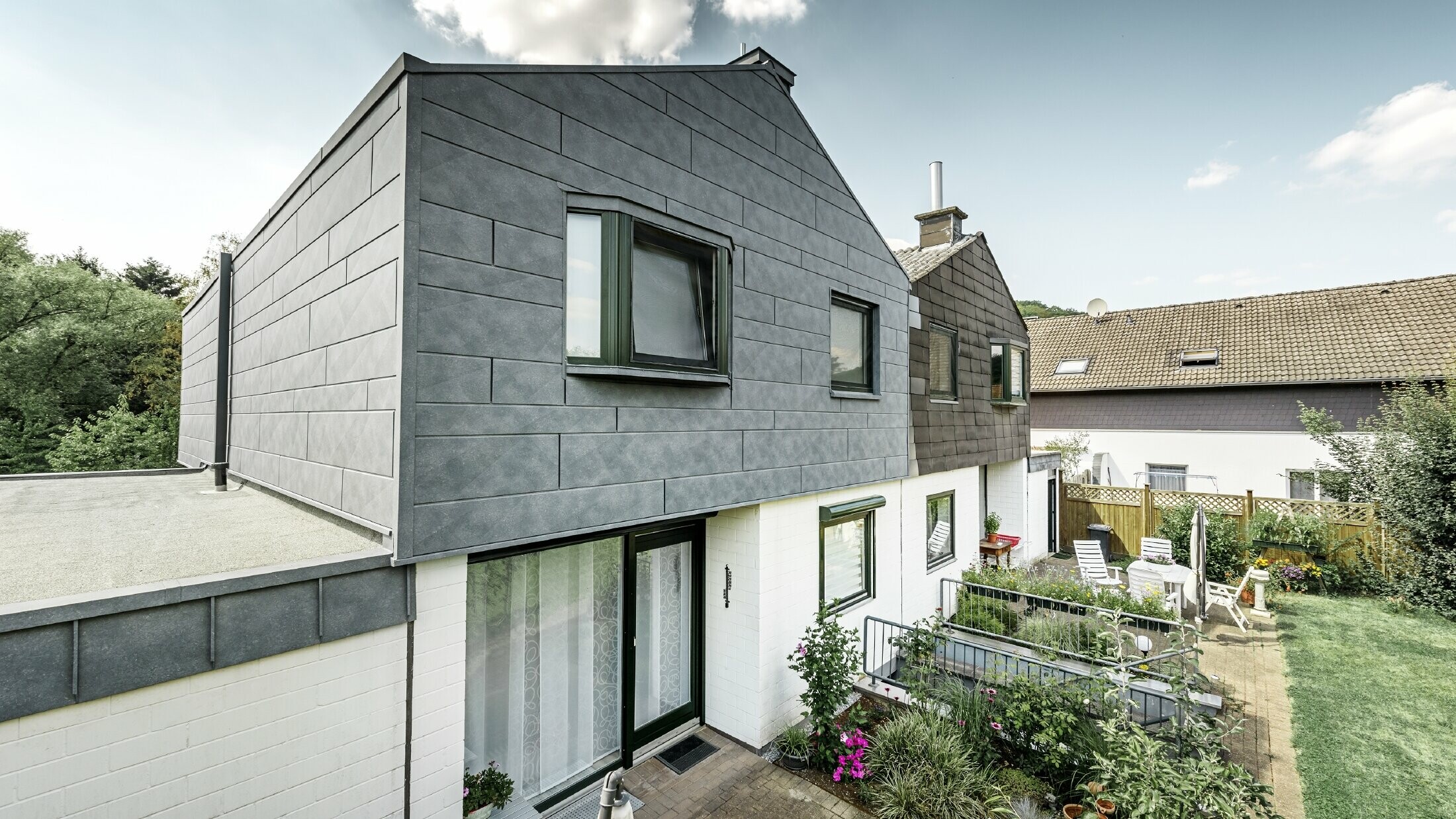 The upper part of the semi-detached house was refurbished with the PREFA Siding.X façade element in P.10 stone grey. Next to it is the semi-detached house before the refurbishment for comparison.