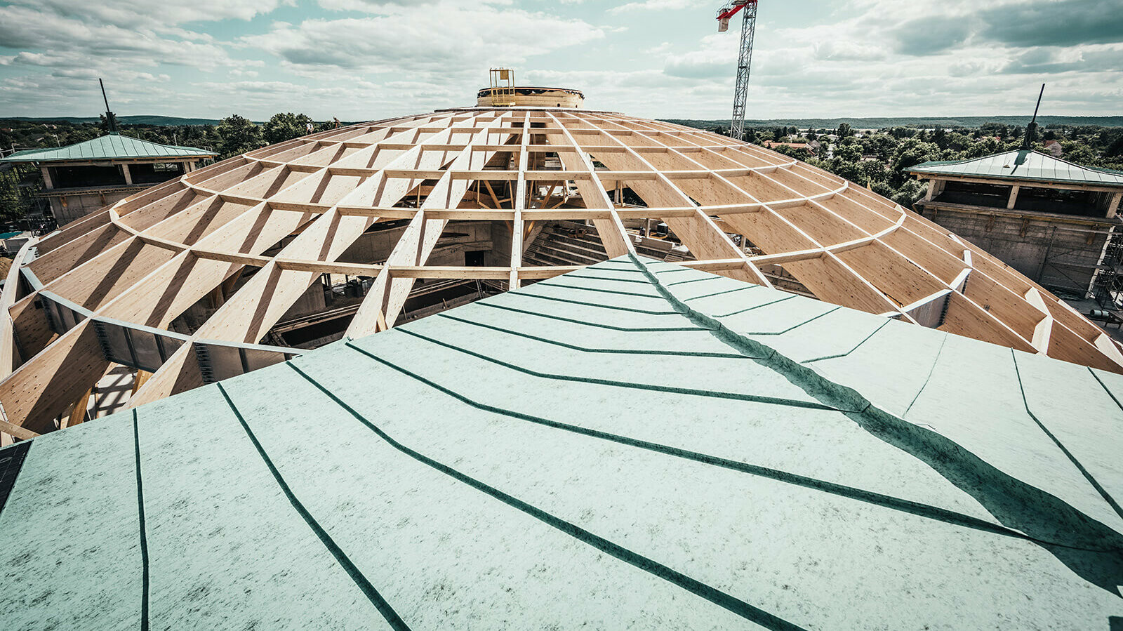 On the picture you can see the biggest laminated cupola in Hungary in the process of completion. In the foreground is the Prefalz roof in patina green. 
