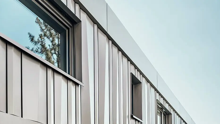 Lateral view of the detached house. The façade is covered with color aluminium coils in bronze. 