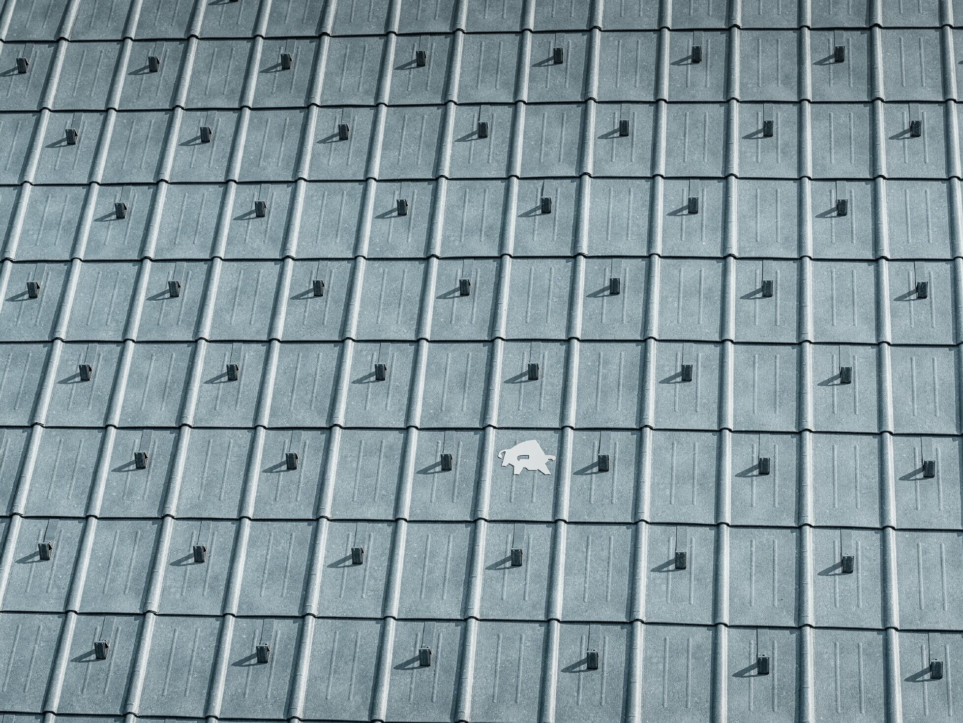 PREFA roof panel laid with PREFA bull logo in P.10 stone grey; roof surface with PREFA sheet metal roof