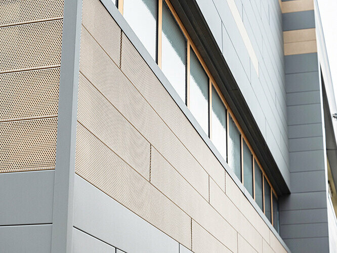 The façade panels from PREFA, siding, are now also available in perforated versions, sand-brown perforated elements are combined with grey panels here. 