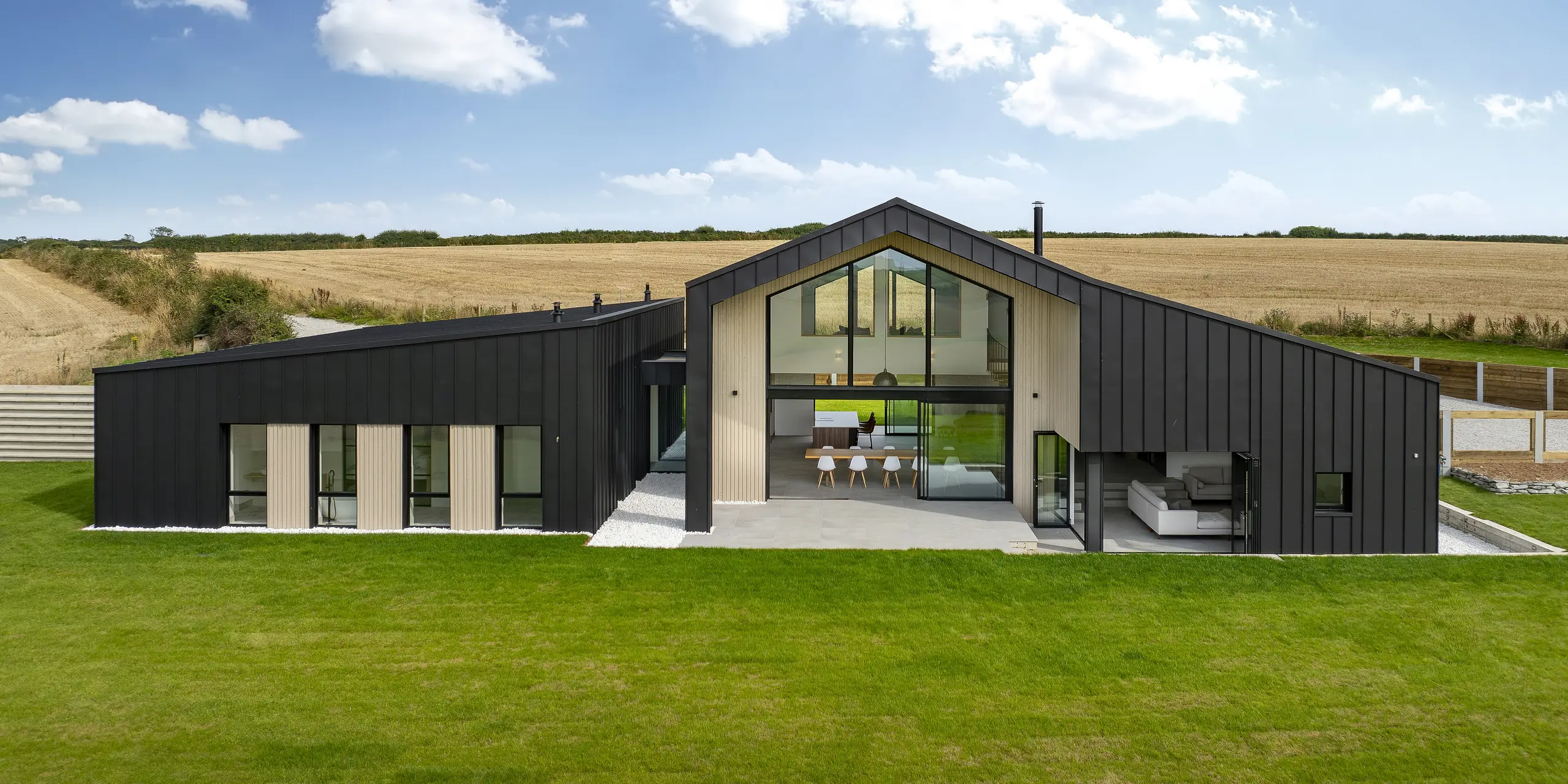 Frontal view of the back of ‘The Hide’ in Cornwall. The generous glass façade, framed by PREFALZ aluminium cladding in P.10 anthracite, opens up the interior to the spacious garden. The clear standing seam look in combination with natural wooden elements emphasises the modern and harmonious design.