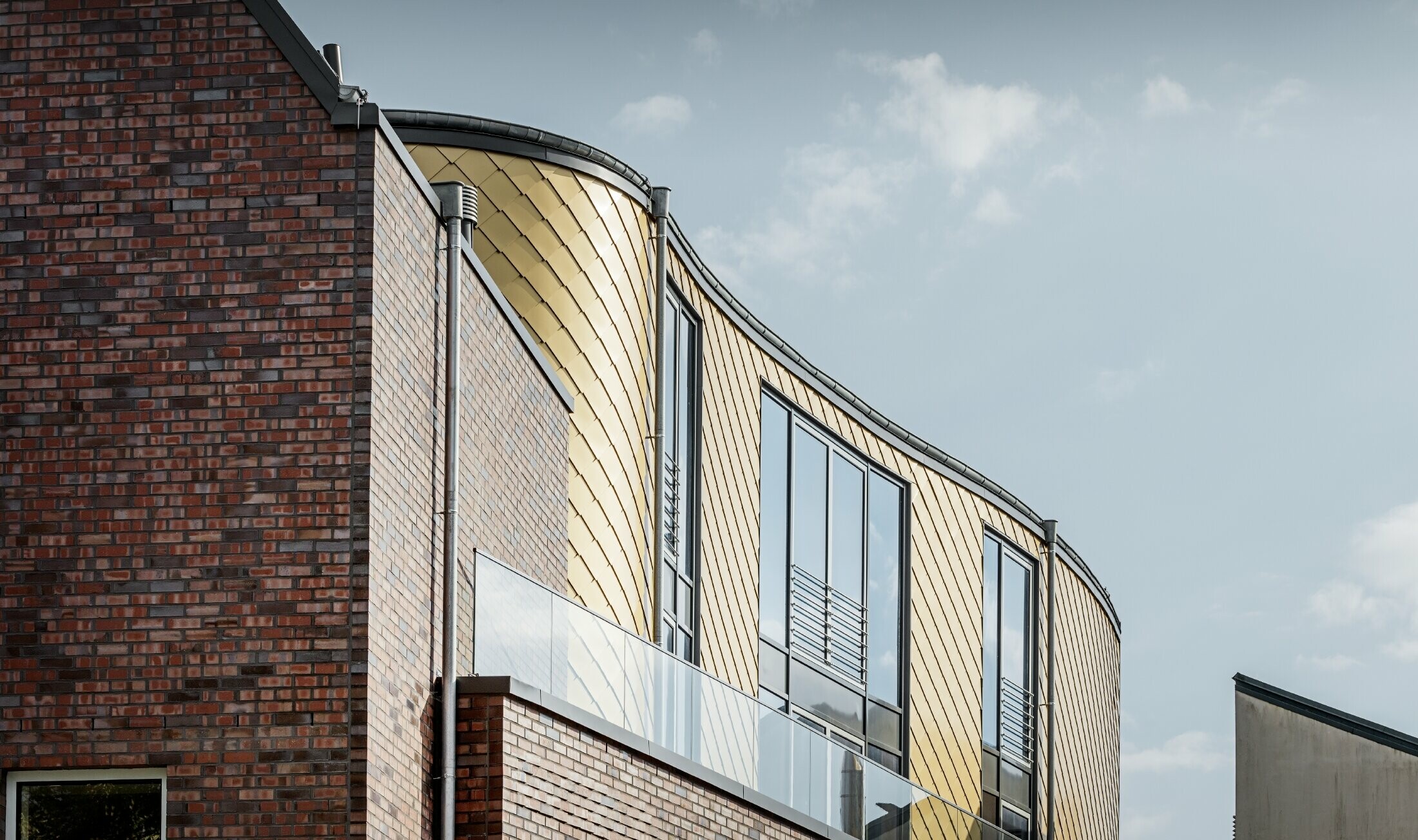 Curved façade of the Schuhhaus Schüttfort shoe store. The façade was clad in the PREFA aluminium rhomboid tile in Mayan gold.