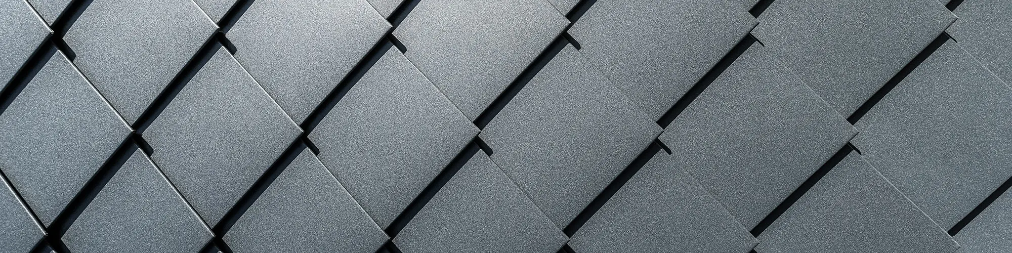 A close-up of the façade with the precisely laid, anthracite-coloured rhomboid facade tiles.