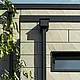 Modernes Einfamilienhaus mit Flachdach und schmalen Fenstern. Die Fassade ist mit der PREFA Siding.X Fassade im faltigen Look in der Farbe Bronze verkleidet. Die Anschlüsse wurden in Anthrazit gemacht. Zur Dachentwässerung dient das PREFA Quadratrohr mit dem dazu passenden Wasserfangkasten in Anthrazit.