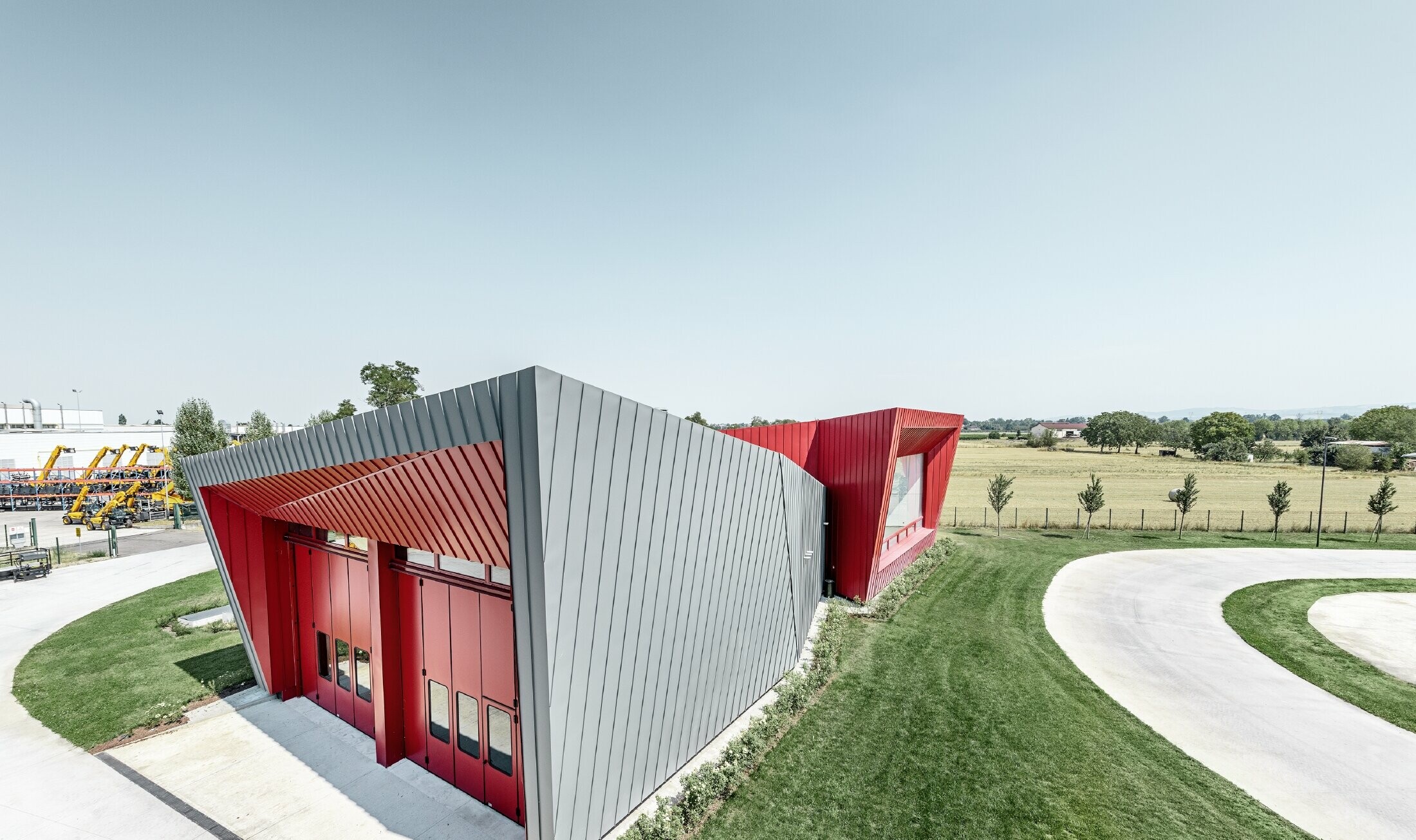 Dieci’s modern training centre in Montecchio Emilia (Italy), with a tribune displaying an aluminium façade in light grey Prefalz and crimson Falzonal