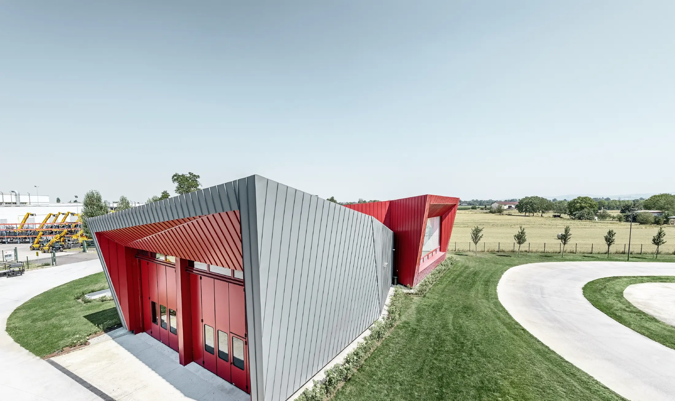 Dieci’s modern training centre in Montecchio Emilia (Italy), with a tribune displaying an aluminium façade in light grey Prefalz and crimson Falzonal