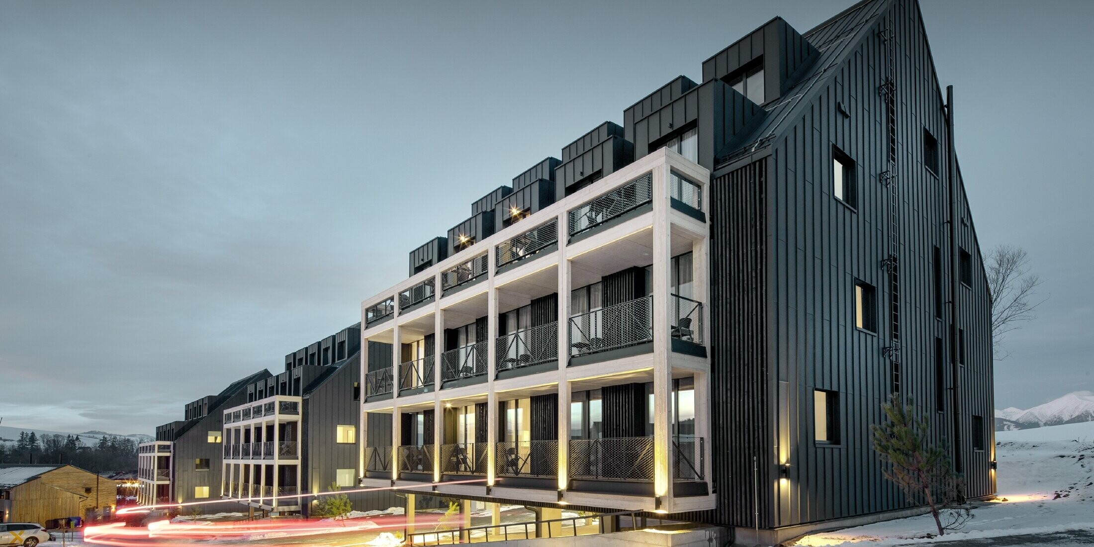 Ski resort in Slovakia with balconies and dormers, the façade is clad with PREFALZ in anthracite, just like the gable roof, snow-covered surroundings