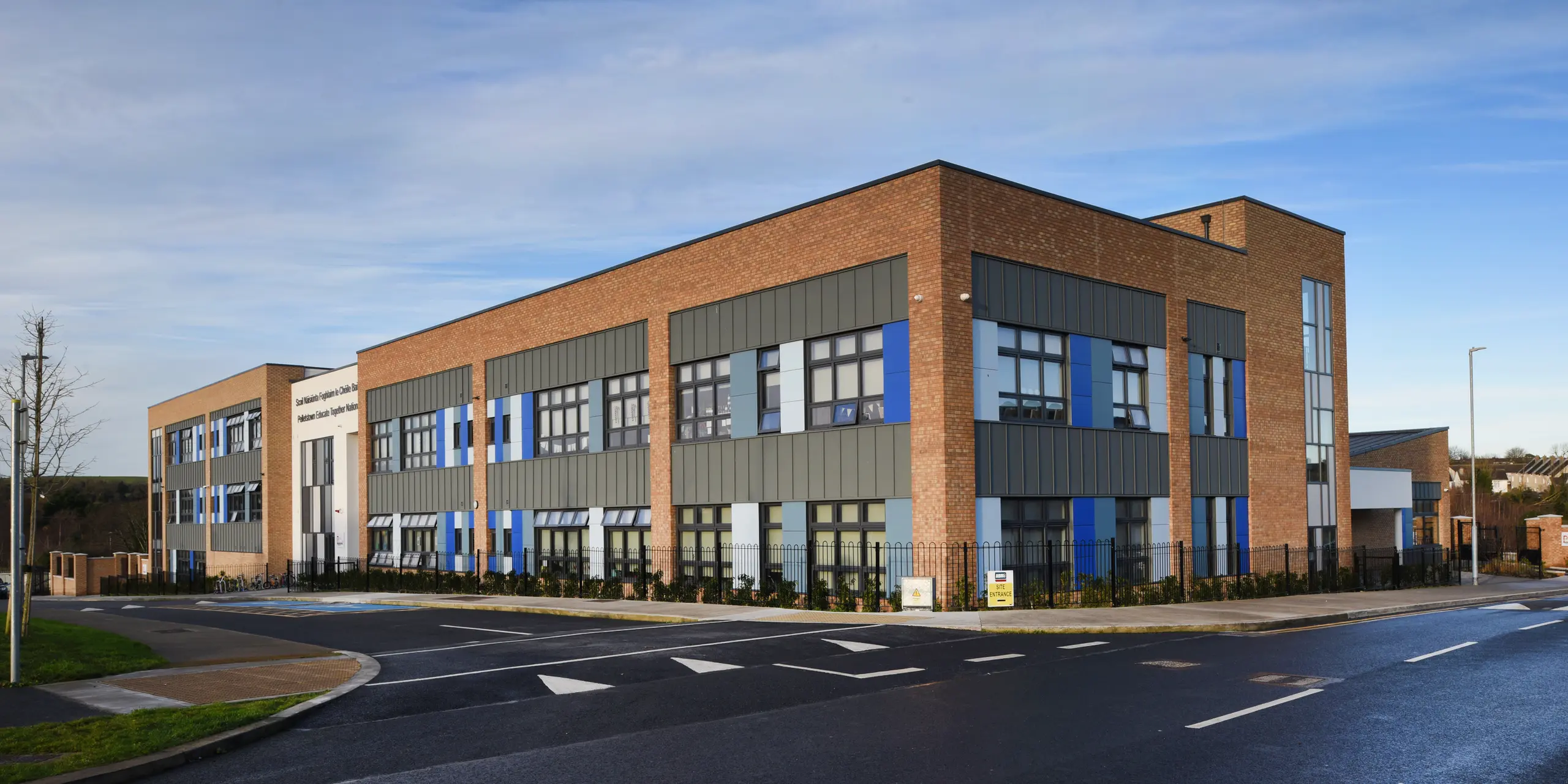 Side view of the Pelletstown Educate Together National School in Dublin, Republic of Ireland. The light grey PREFALZ standing seam cladding forms an elegant and weather-resistant outer skin. The aluminium elements ensure a harmonious transition to the clinker brick and rendered façades - a unique mix of materials.