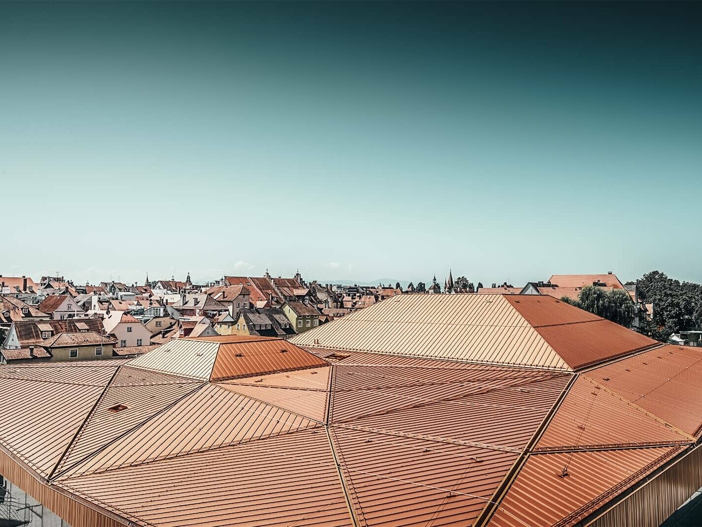 This picture shows a roof landscape of the "Inselhalle" in Lindau which is covered in Falzonal from PREFA in the colour red brown.