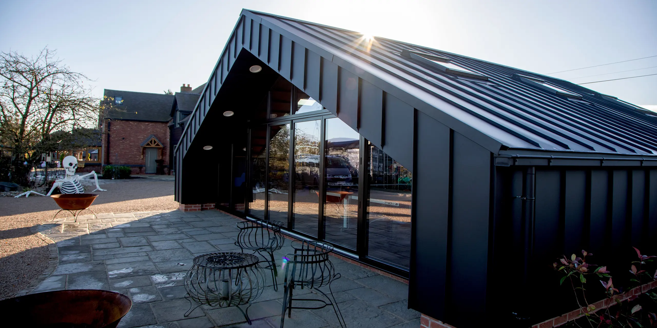 Exterior view of the modern leisure building clad entirely with PREFA aluminum and PREFALZ in P.10 black. The sharp standing seam lines, expansive glass façade and striking roof geometry create a dynamic architectural look. The durable, weather‑resistant aluminum surface ensures long‑lasting performance and enhances the building’s bold presence in the outdoor setting.