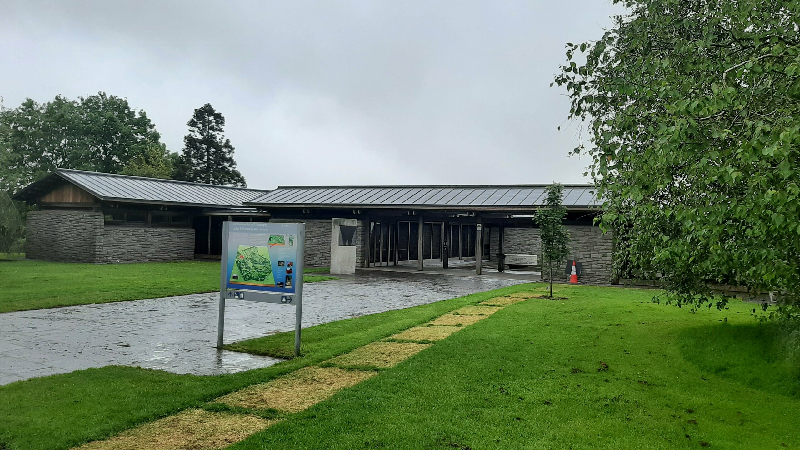 Picture of the new roof of the visitor center with PREFALZ in the colour P.10 dark grey. Around the vistor center you can see a sign and a tree.