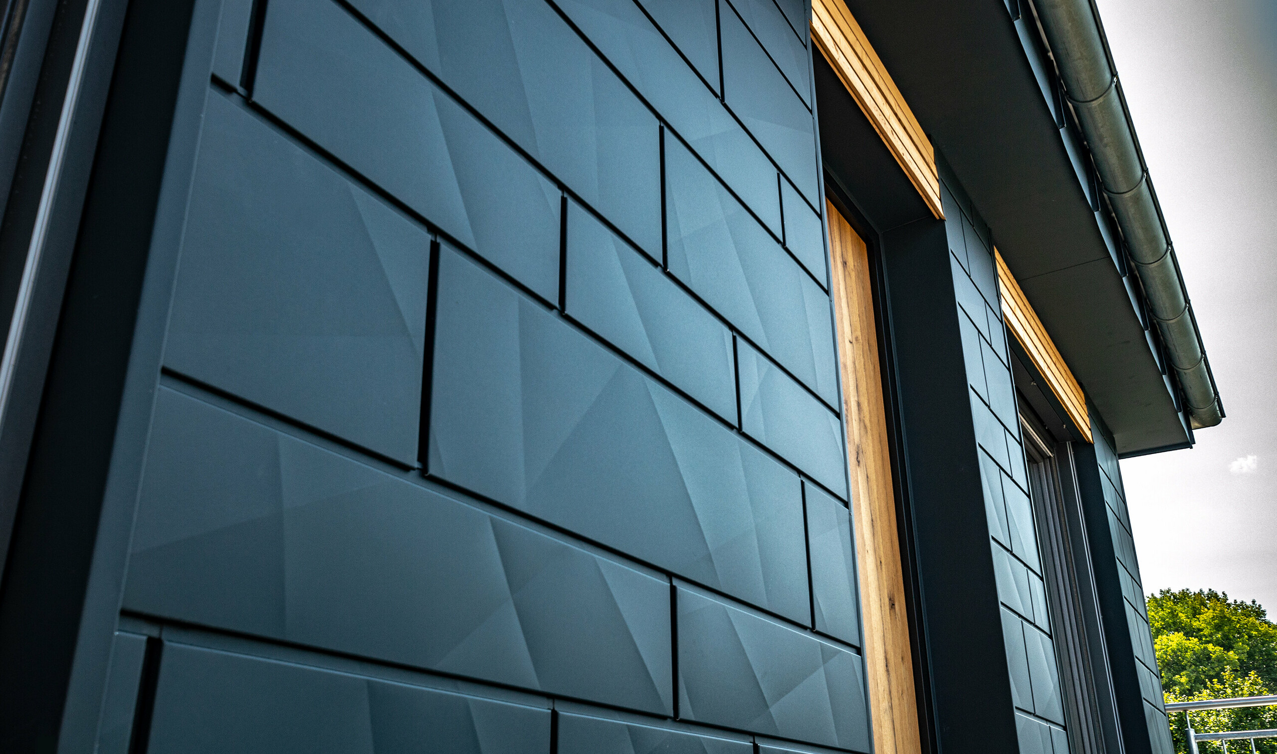 Façade with PREFA Siding.X in anthracite with balcony doors and large glazed areas mixed with a wooden façade.