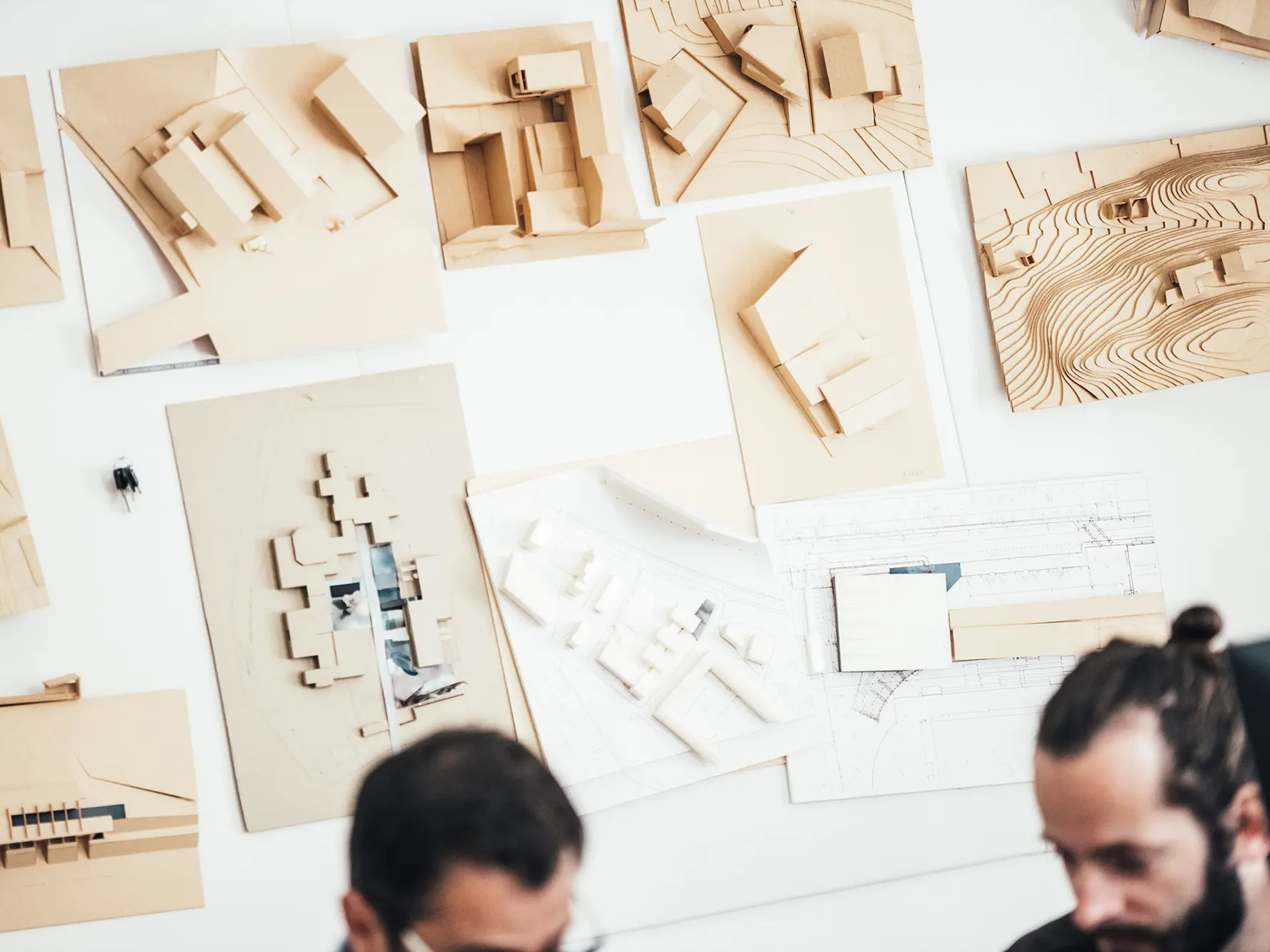 Shot of architectural models on the wall. Out of focus in the foreground: two employees of the office.