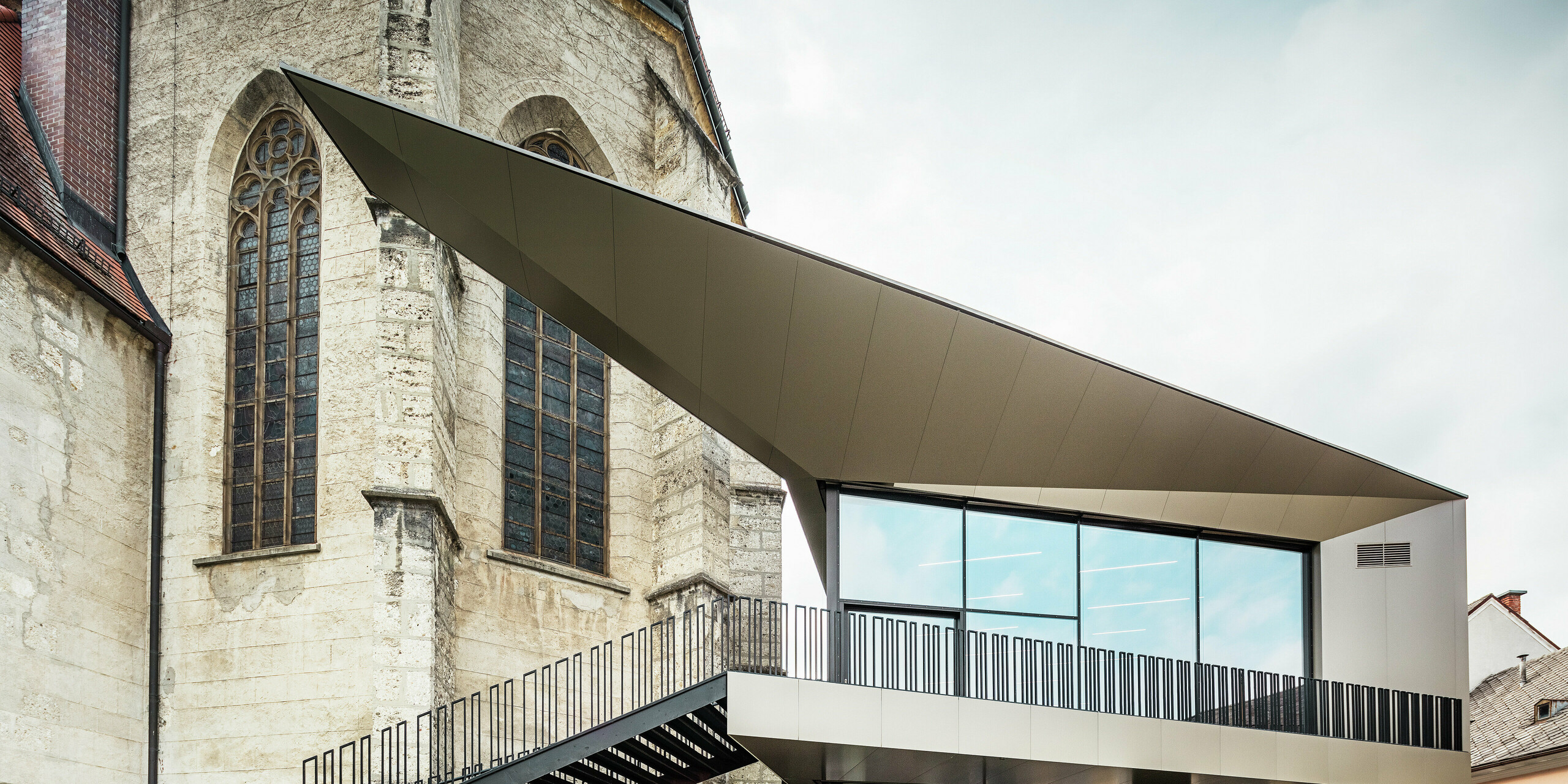Die Rückseite des Pfarrzentrums in Sierning zeigt die Vielseitigkeit von PREFA Aluminium Verbundplatten in Kombination mit Glas. Die fugenlose Montage und die exakte Kantenausbildung unterstützen die architektonische Idee einer schwebenden Struktur mit hoher Widerstandsfähigkeit gegen äußere Einflüsse.
