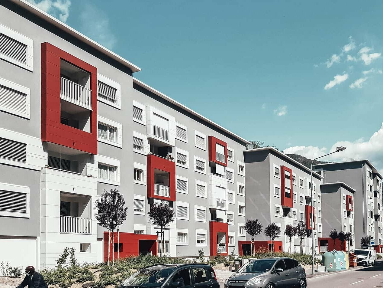 Oblique view of a residential building in Bolzano, Italy, with the Prefalz façade system from PREFA in the colours Oxydro red and Prefa white.