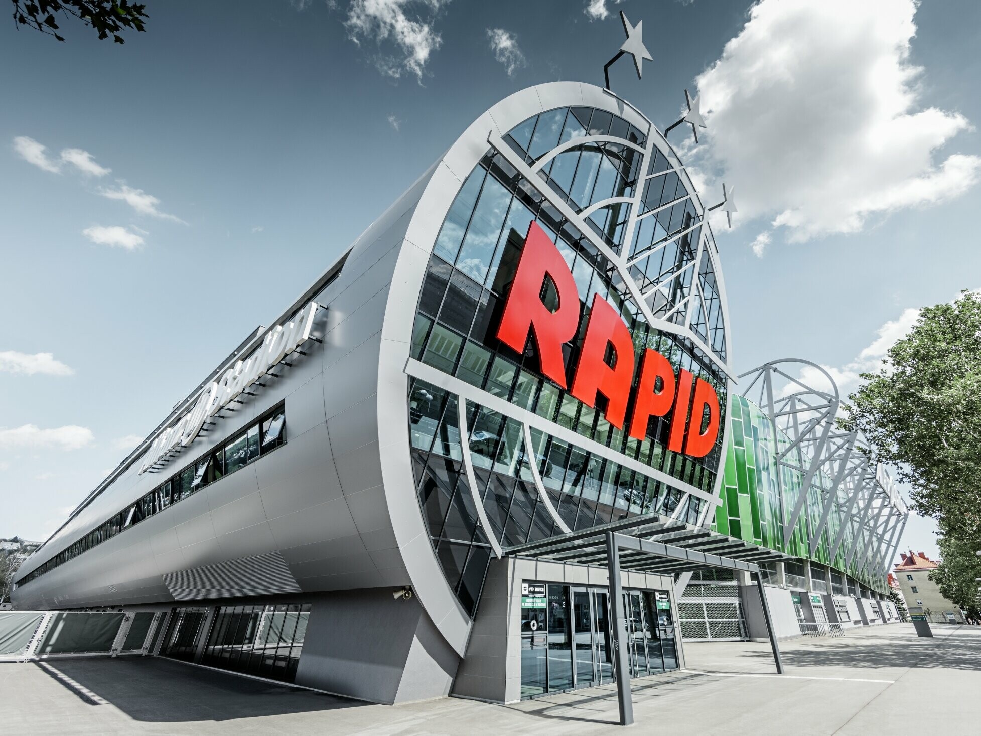 The entrance to the Allianz Stadium with the large logo for SK Rapid in Vienna. The tube with the large glass façade is covered with the PREFA aluminium composite tile in metallic silver.