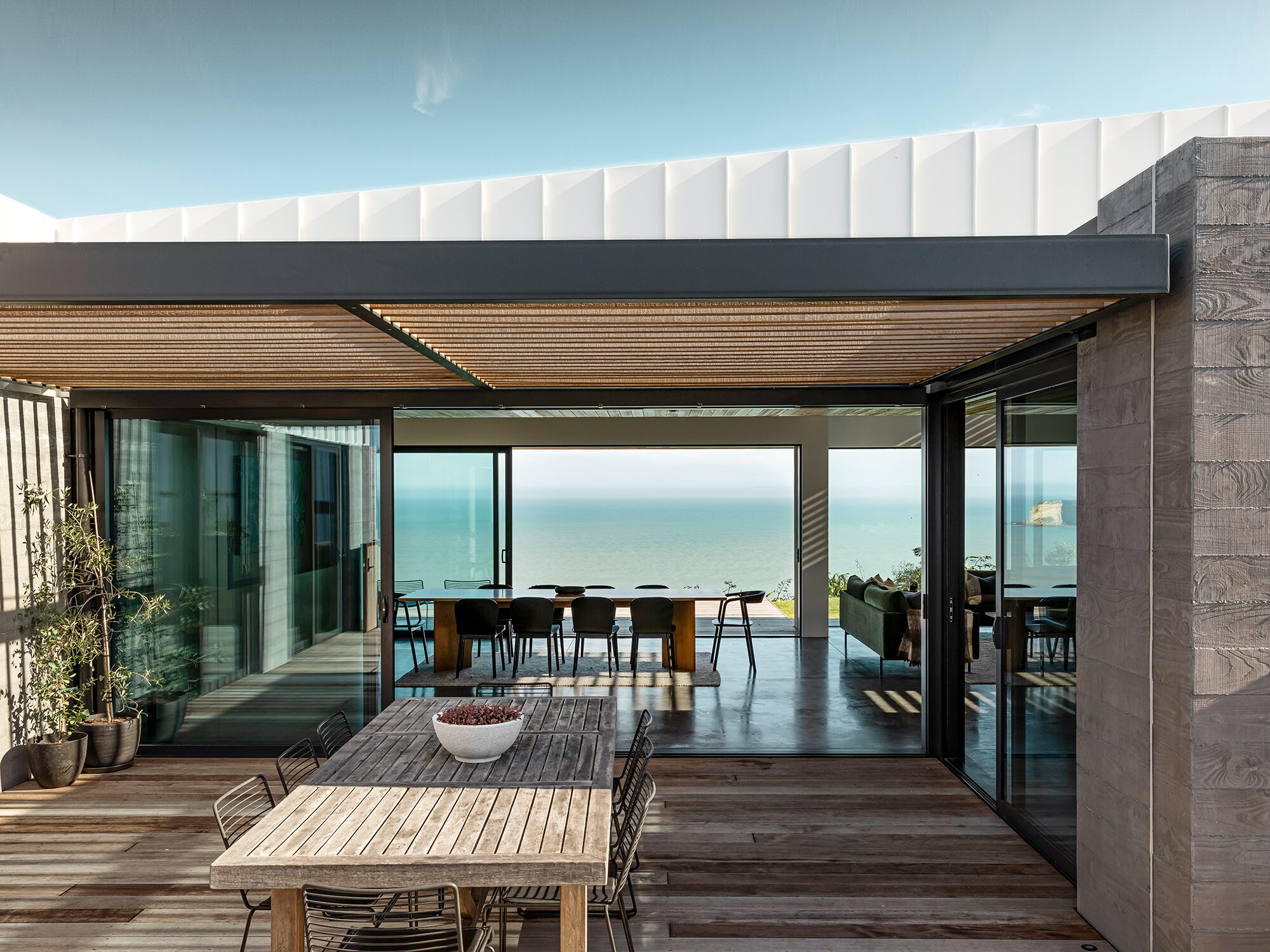 View into the living area that is extended through the terrace in the front and the back. The ocean stretches out behind it.