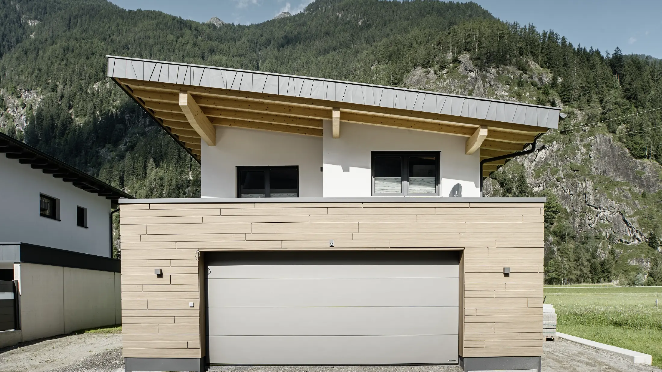 Modern new build with monopitch roof and customised verge cladding, garage with flat roof and aluminium façade in walnut from PREFA. The siding was installed horizontally and with different visible widths.