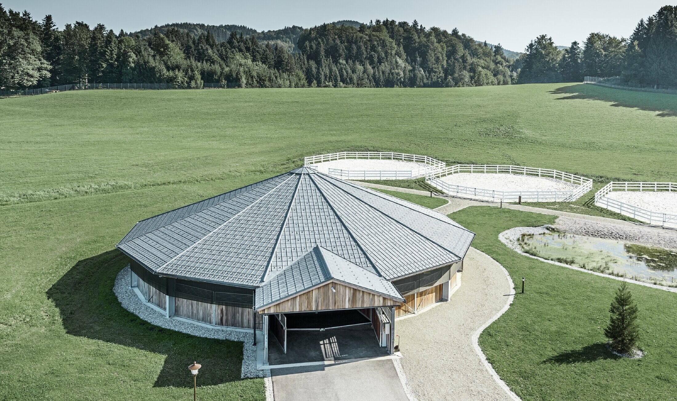 Round riding arena clad in the PREFA roof tile in stone grey
