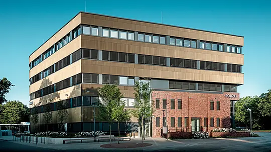 Markante Außenansicht des Polizeikommissariats 43 in Hamburg: Der präzise gegliederte Neubau schwebt förmlich über dem Backsteinbestand und beeindruckt mit einer PREFA Aluminiumfassade aus Strangpressprofilen „Zacke“ in edlem Mittelbronze. Die fein strukturierte Oberfläche erzeugt je nach Lichteinfall lebendige Reflexionen und verleiht dem Baukörper Tiefe sowie Dynamik. Als architektonischer Eyecatcher verbindet die Fassade modernes Design mit Vorteilen wie hoher Korrosionsbeständigkeit, Langlebigkeit und minimalem Wartungsaufwand.