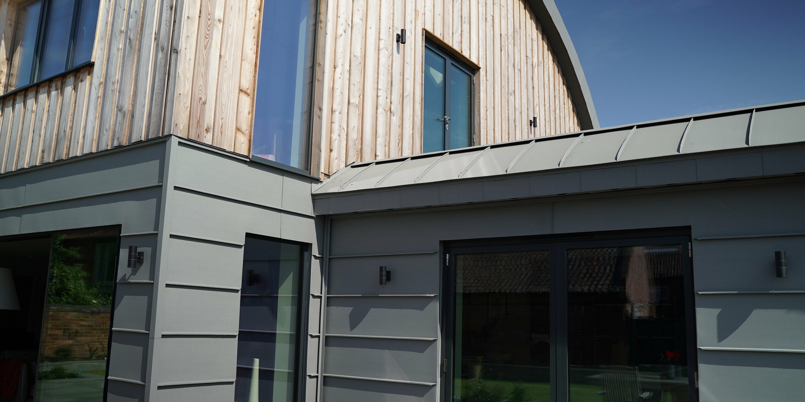 Dutch barn in steel frame construction wrapped with PREFALZ in patina grey and wood