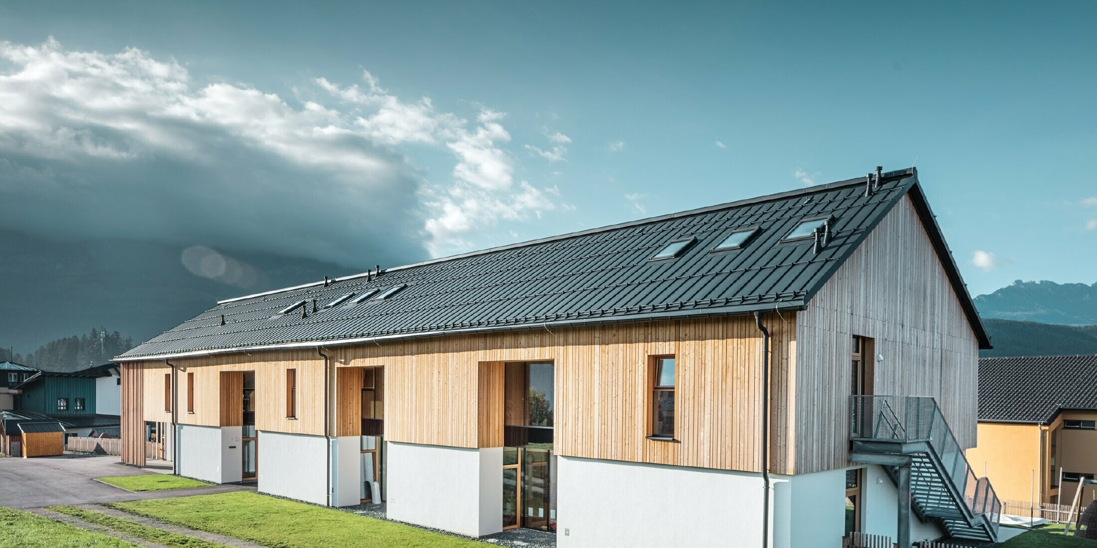 Wide-angle view of the kindergarten, façade in wood look, the roof covered in Prefalz P.10 anthracite