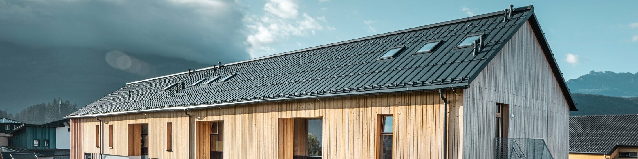 Wide-angle view of the kindergarten, façade in wood look, the roof covered in Prefalz P.10 anthracite