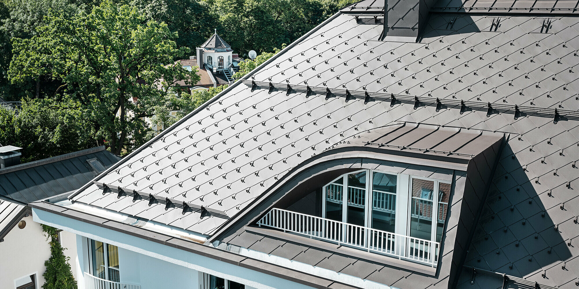Apartment building with PREFA rhomboid roof tiles 44 × 44 in brown with snow guards and snow rakes