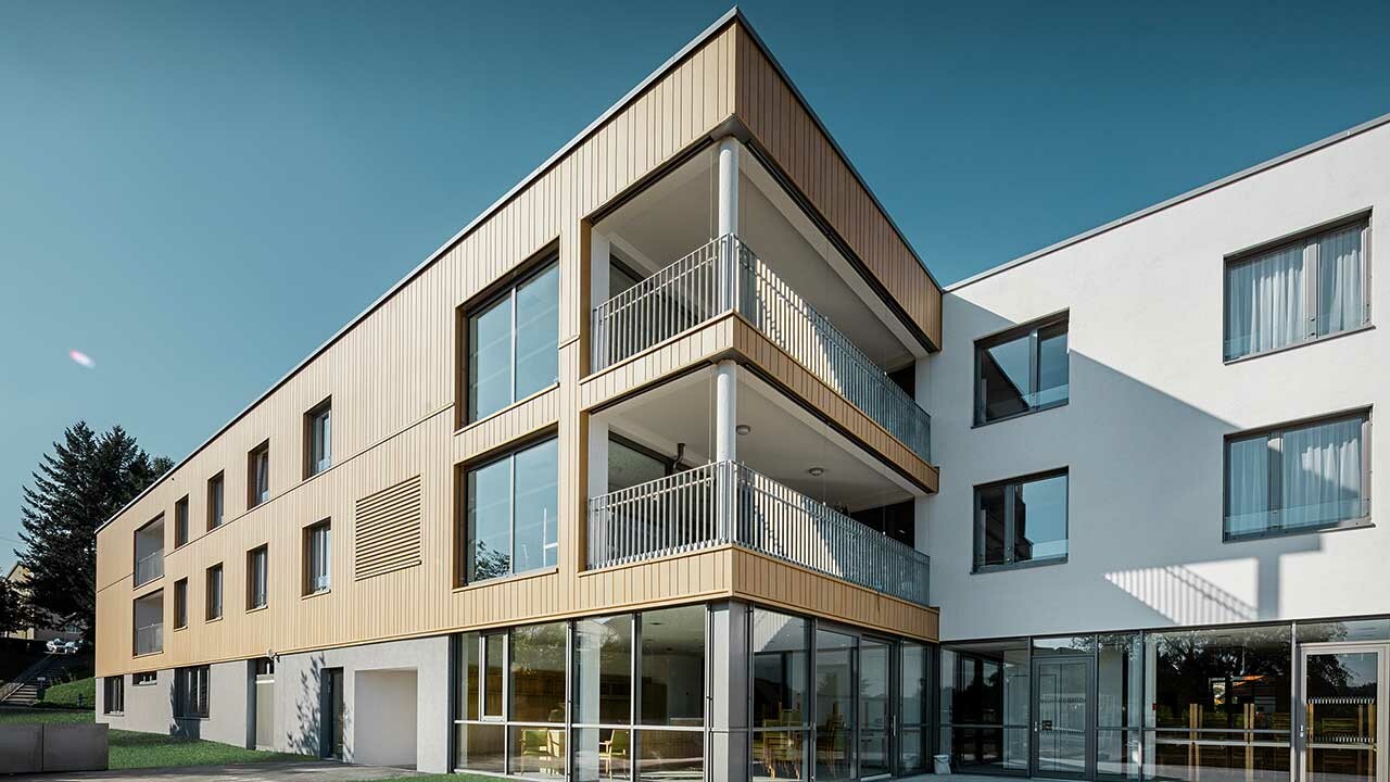 Retirement home with a flat roof and a sand brown siding façade made by PREFA
