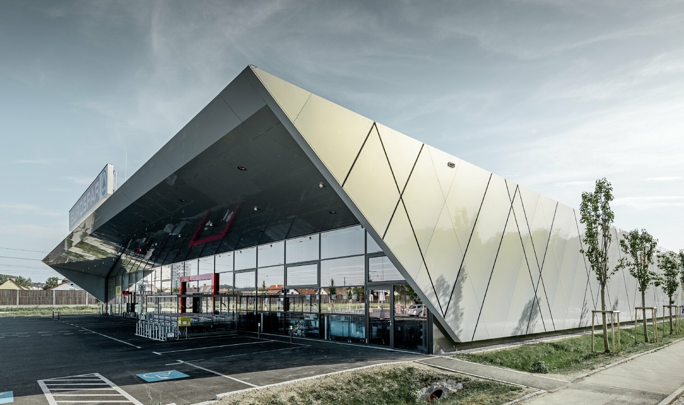 Entrance area of the new Eurospar store in Wels with a modern PREFA façade tile in silver gold. The composite aluminium tiles shimmer in different colours depending on the angle of the sun.