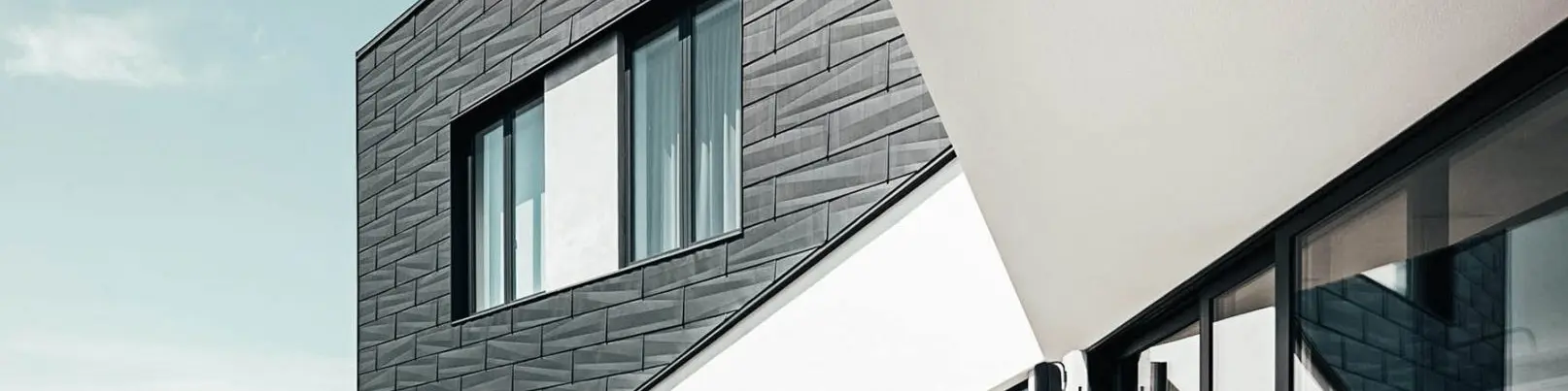 Lateral view of the Triangle house, covered in Prefa Siding.X façade panels in P.10 anthracite. A short section of the garden can be seen on the left side. 