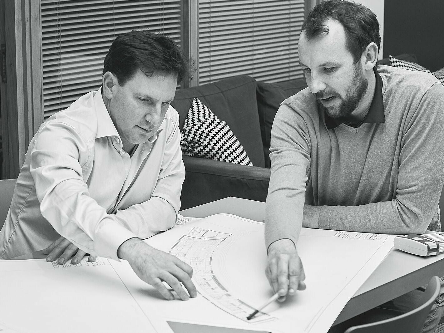 Black and white image of two architects from Adrian Hill Architects looking at a plan