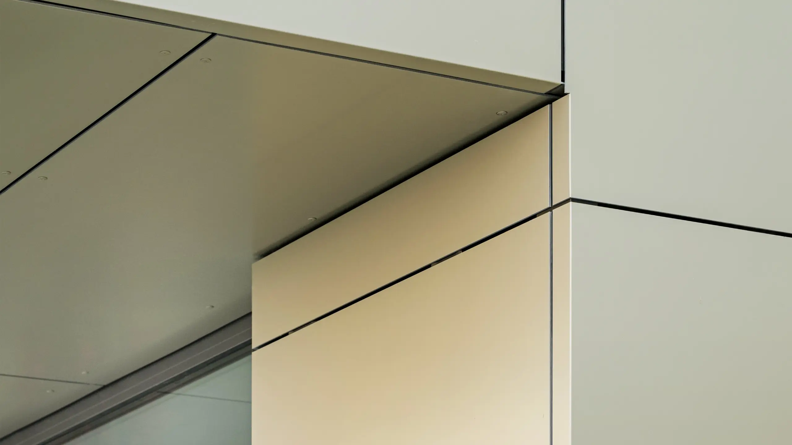Close-up of the façade of the town hall in Alzenau, showing the precise edges and transitions of the PREFA aluminium composite panels in bronze colour. The panels are perfectly joined together, creating clean, modern lines. The metallic sheen of the panels is emphasised by the fine joint lines and minimalist details of the architecture, giving the façade an elegant and contemporary look.