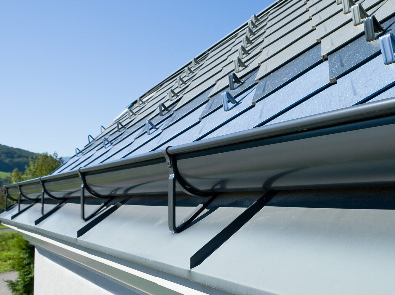 The PREFA on-roof gutter,   mounted with suitable gutter brackets on a PREFA rhomboid tile roof.