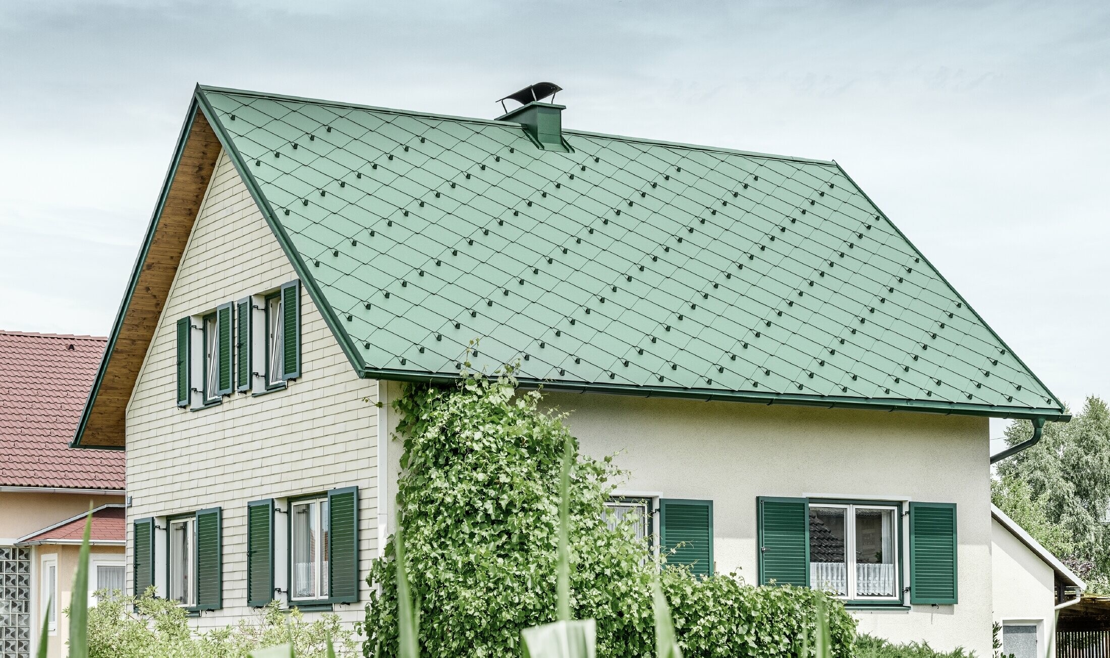 Classic detached house with a gable roof with an aluminium roof covering in moss green with green shutters