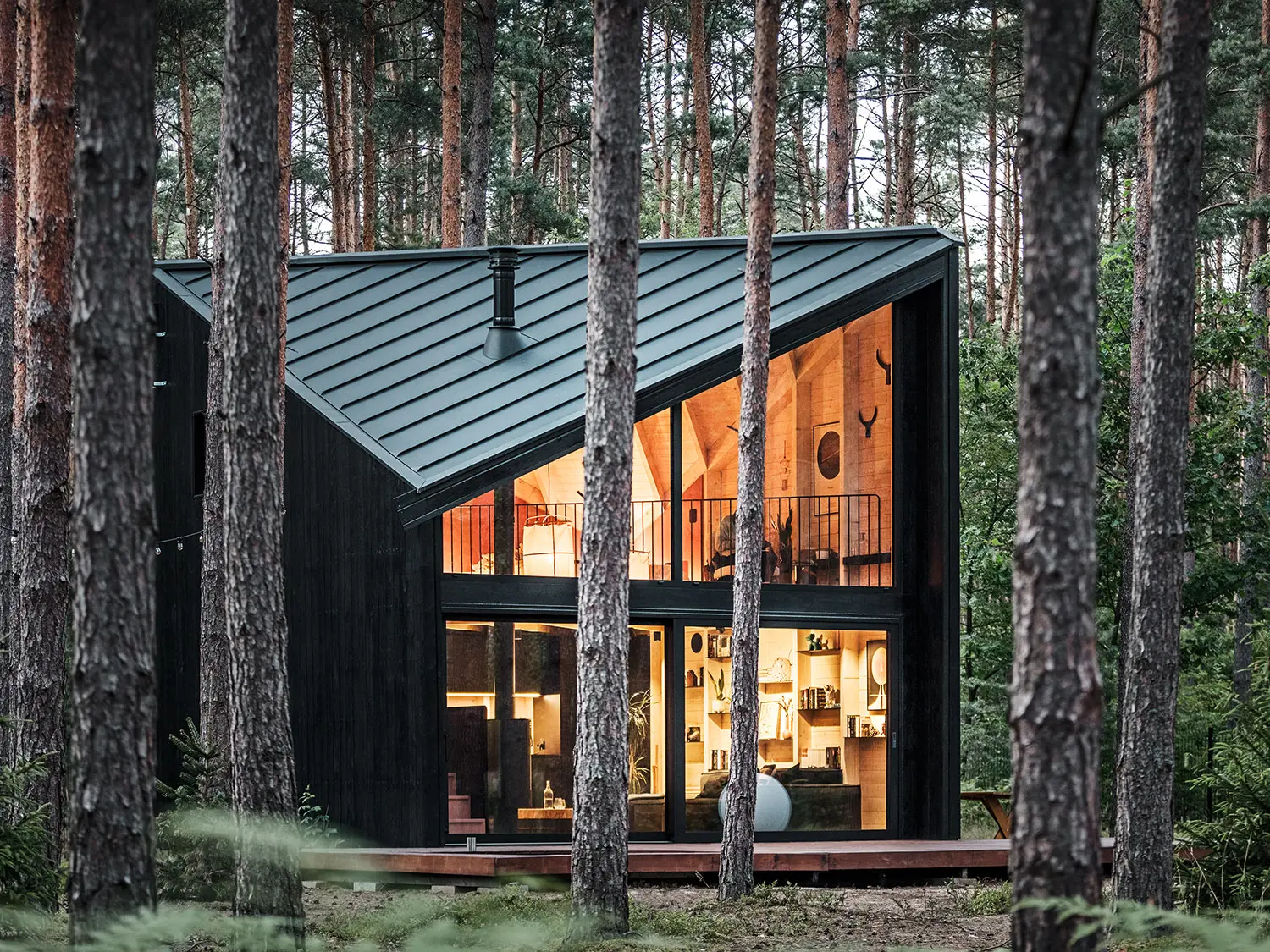 Side view of the glazed building front and into its lighted, Scandinavian-inspired interior.