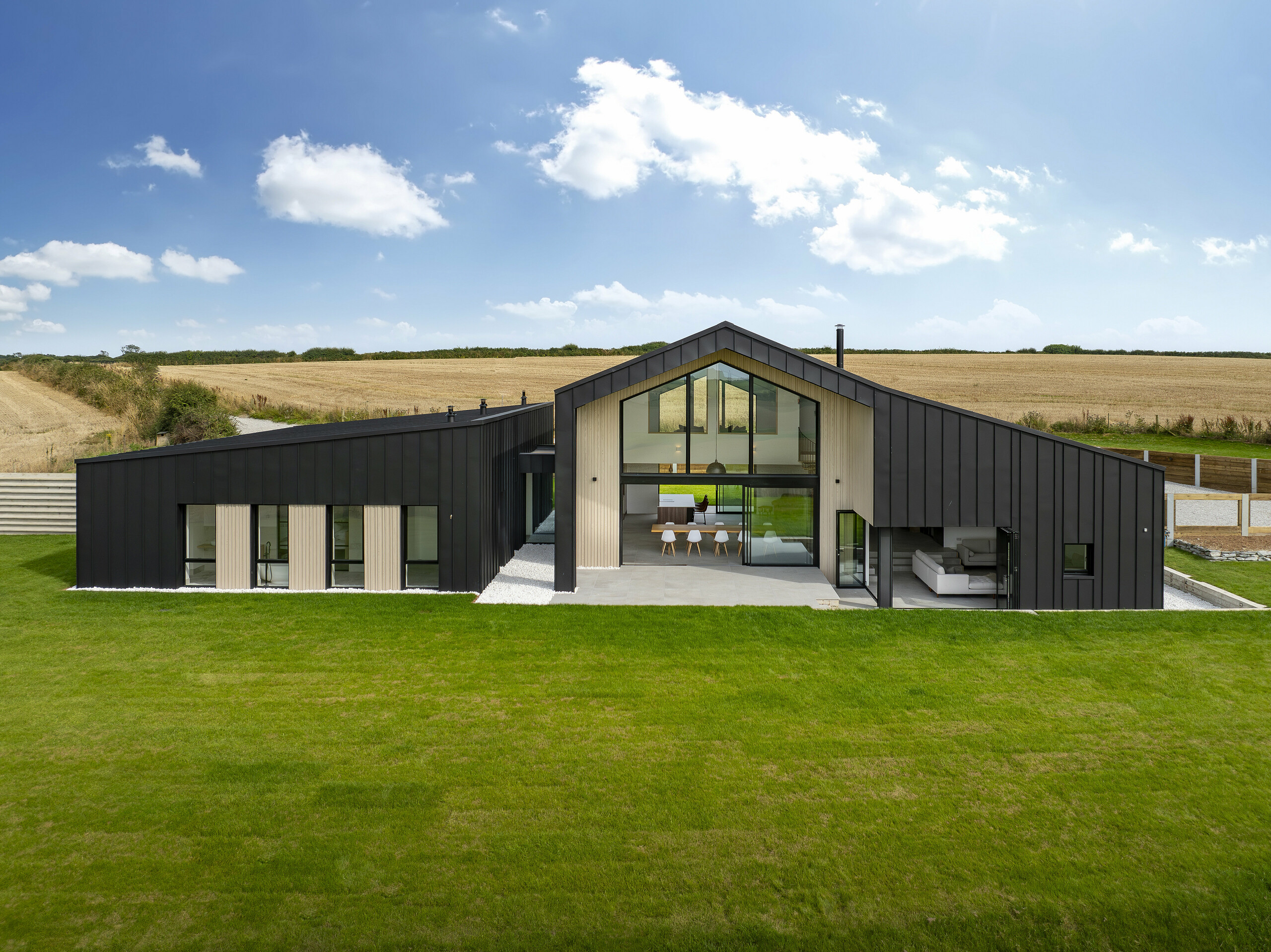 Frontal view of the back of ‘The Hide’ in Cornwall. The generous glass façade, framed by PREFALZ aluminium cladding in P.10 anthracite, opens up the interior to the spacious garden. The clear standing seam look in combination with natural wooden elements emphasises the modern and harmonious design.