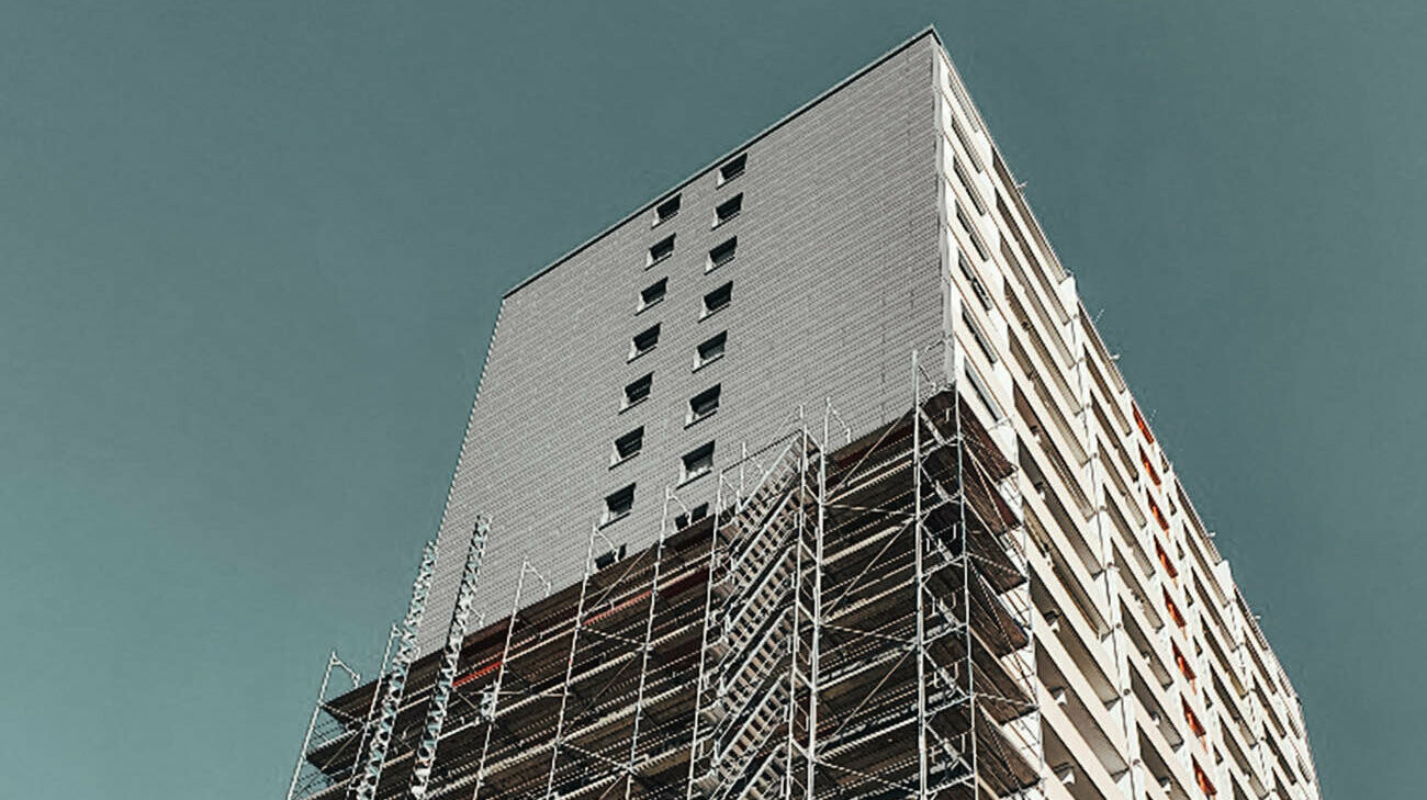 Lateral view of the high-rise during the façade renovation. The scaffold around the building can be seen.