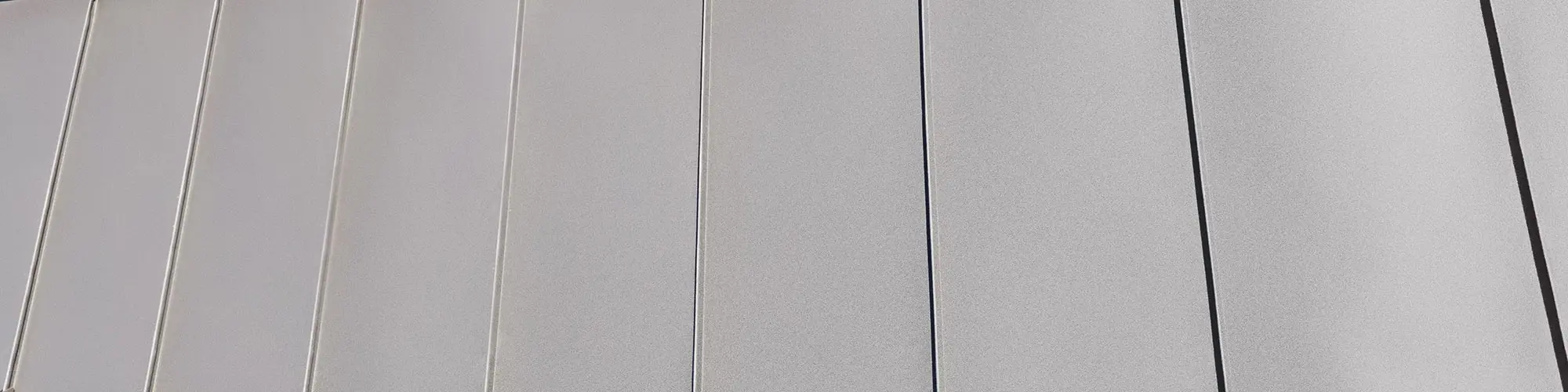 Close-up of the nutbrown, vertically aligned Prefalz sheets of the complex roof on the multi-family house Matino.