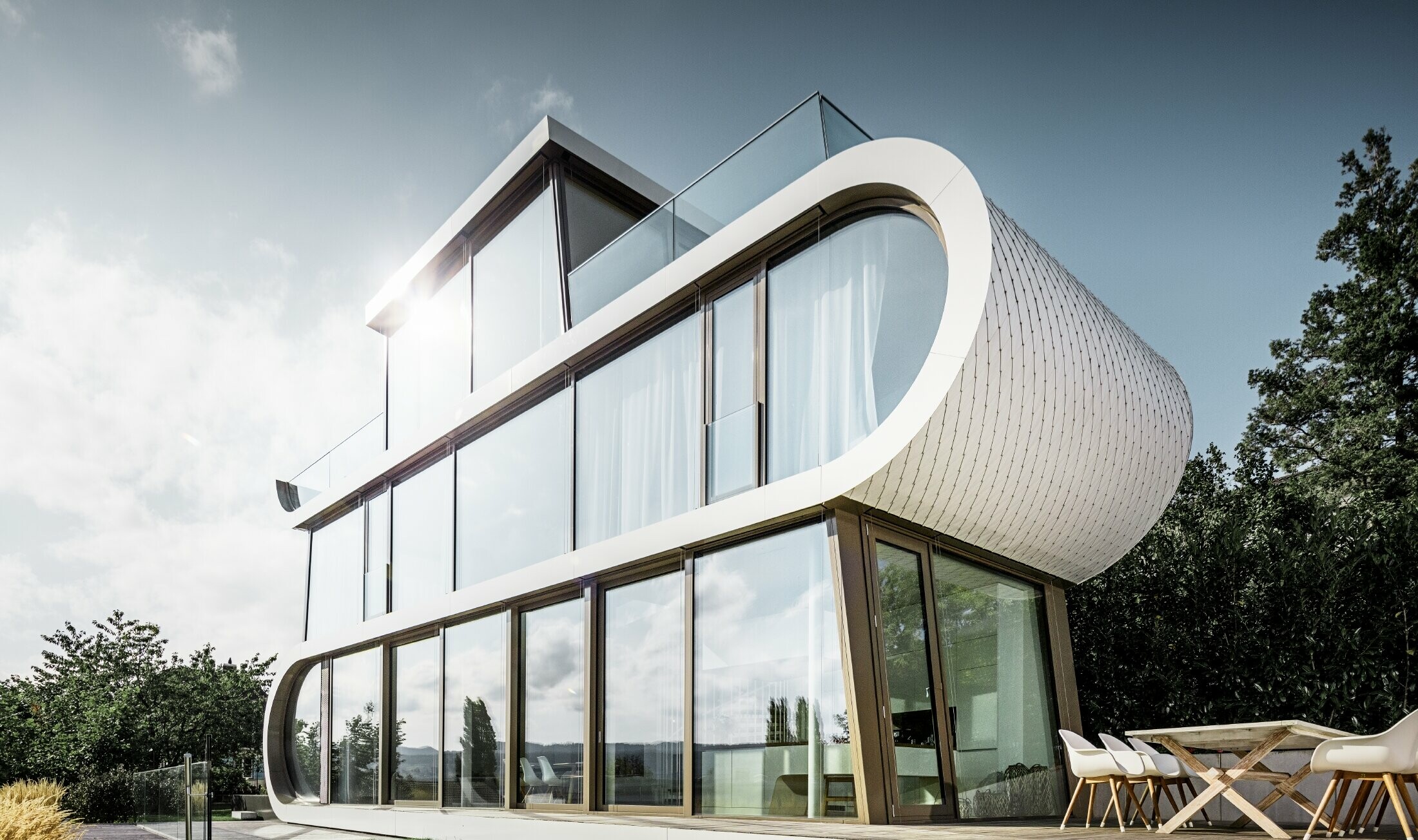 Modern detached house designed by the architect Camenzind. A curved truss connects the levels – on the outsides, the curve is clad in the easy to install PREFA small rhomboid roof tiles in pure white.