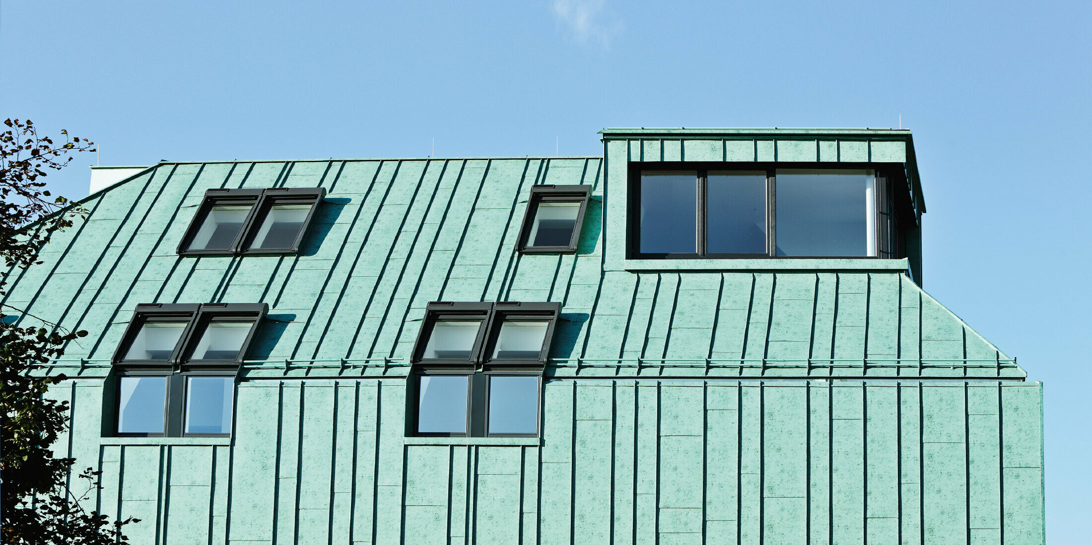 Roof and façade design with PREFALZ in patina green from PREFA in different panel widths.