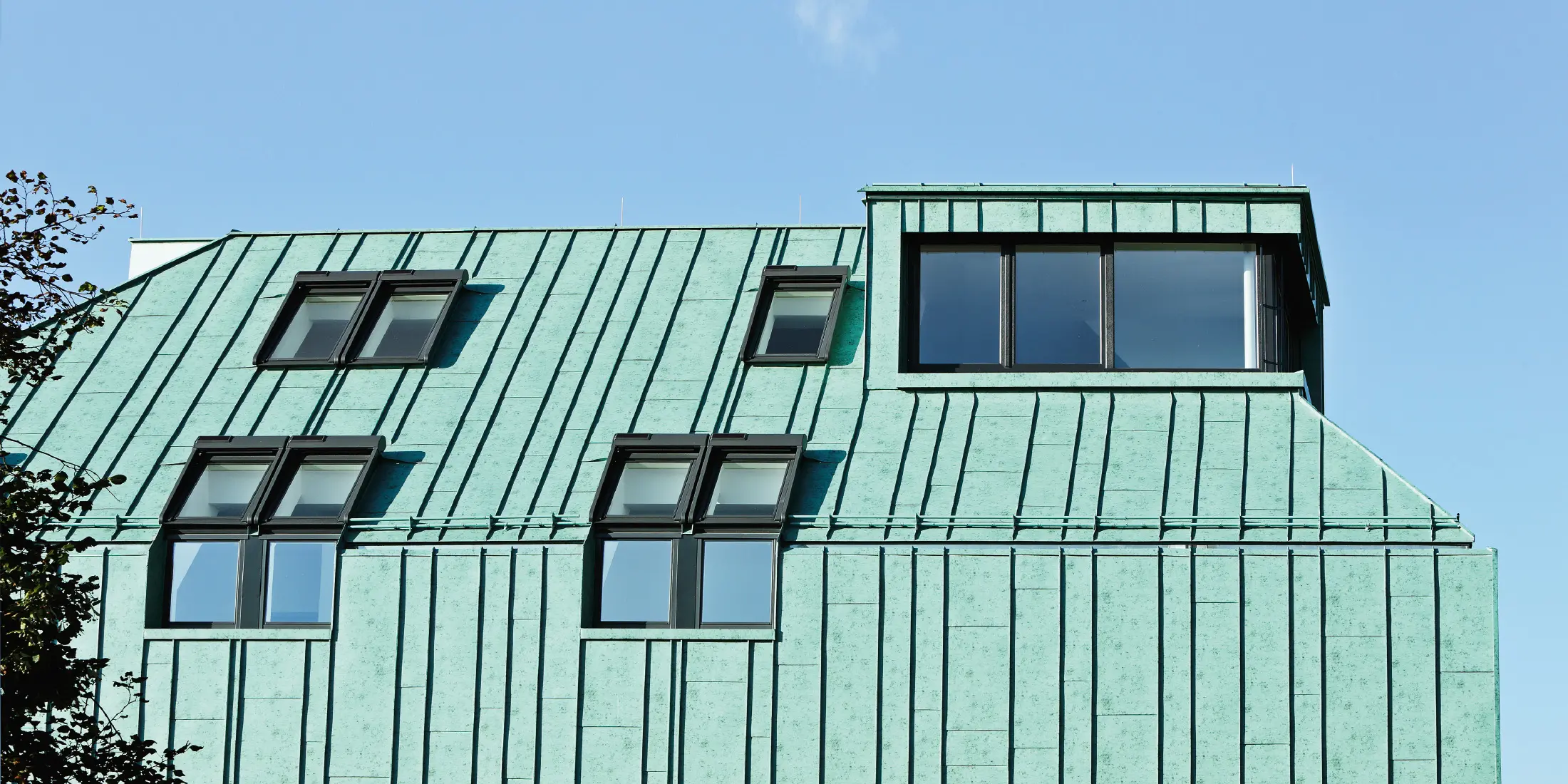 Roof and façade design with PREFALZ standing seam in patina green from PREFA in different panel widths.