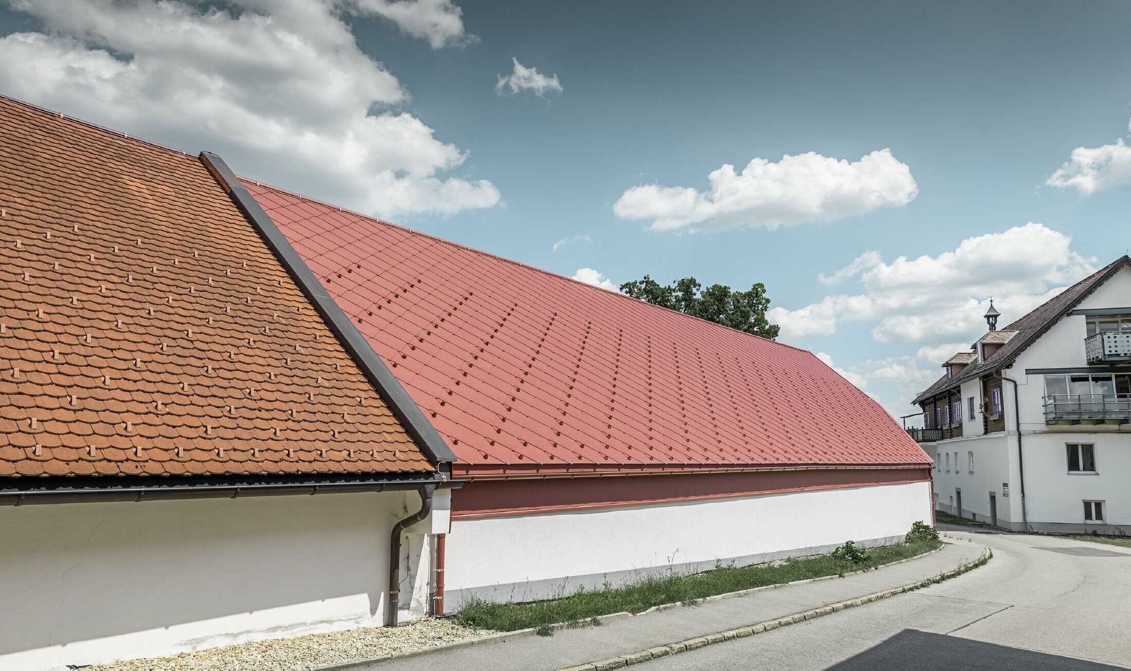 Exterior view of the Kerzenwelt candle store in Schlägl; the roof was covered with the large PREFA 44 x 44 aluminium rhomboid tile in oxide red.