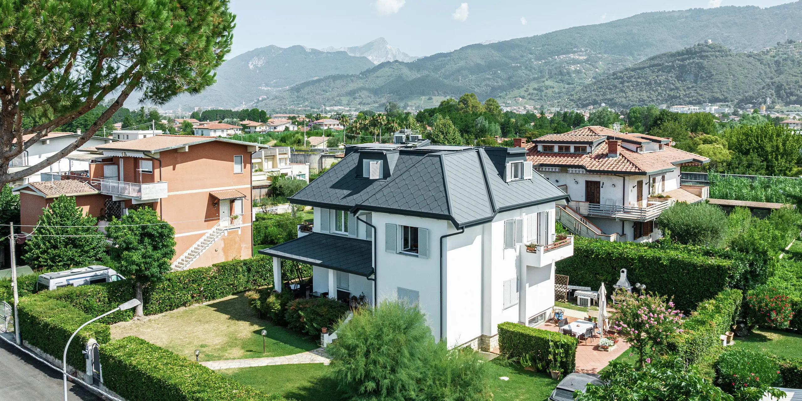 Das elegante Einfamilienhaus im italienischen Montignoso beeindruckt mit einer hochwertigen PREFA Dacheindeckung aus robustem Aluminium. Die PREFA Dachraute 44 × 44 in P.10 Steingrau sorgt für eine moderne, witterungsbeständige und langlebige Lösung. Das Aluminiumdach fügt sich harmonisch in die mediterrane Umgebung ein und bietet optimalen Schutz vor Sturm, Korrosion und UV-Strahlung. Die präzise Verarbeitung und das stilvolle Design unterstreichen die hohe Qualität der PREFA Produkte.