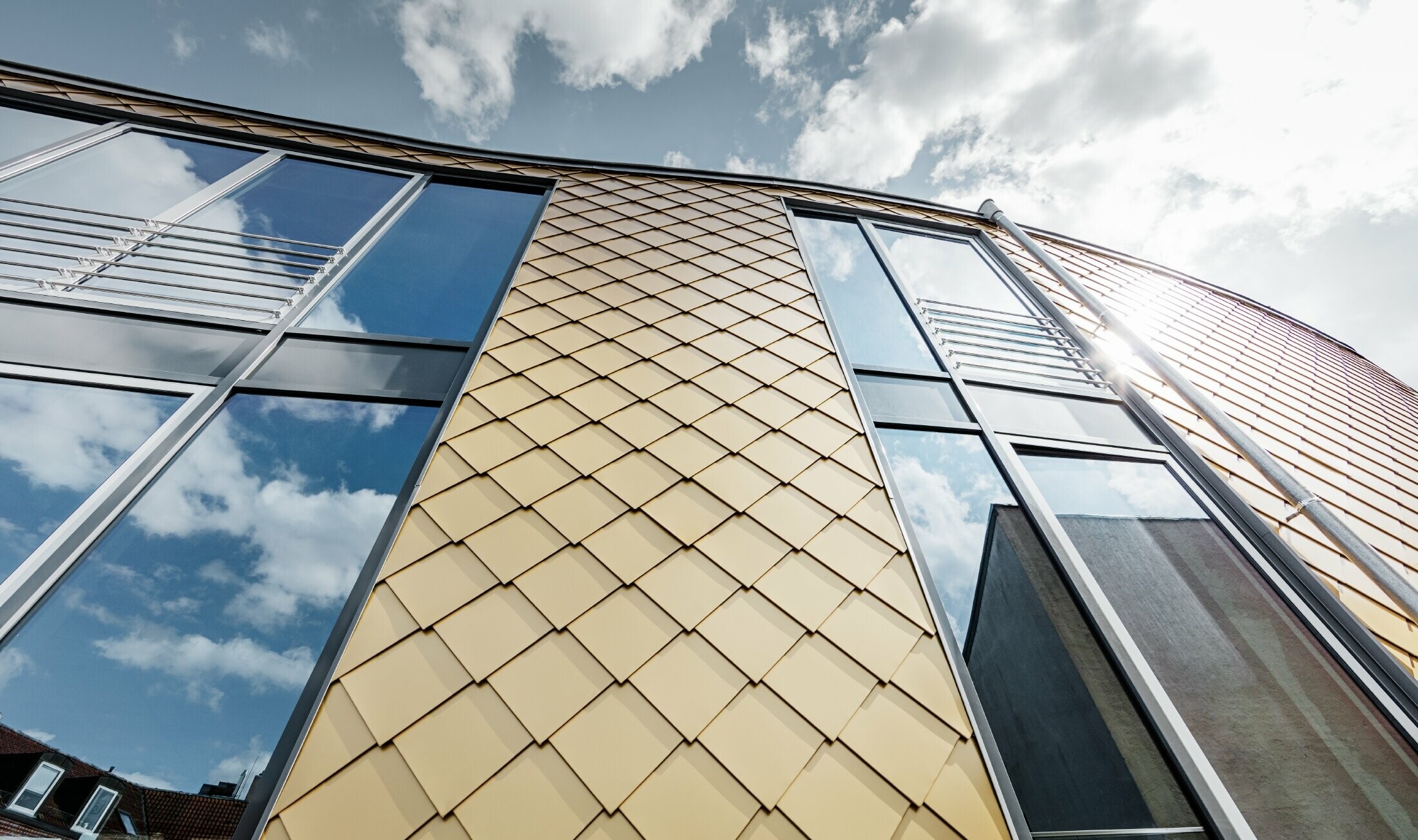 PREFA golden aluminium rhomboid tile in Mayan gold. The large glazed areas on the façade of the office building.