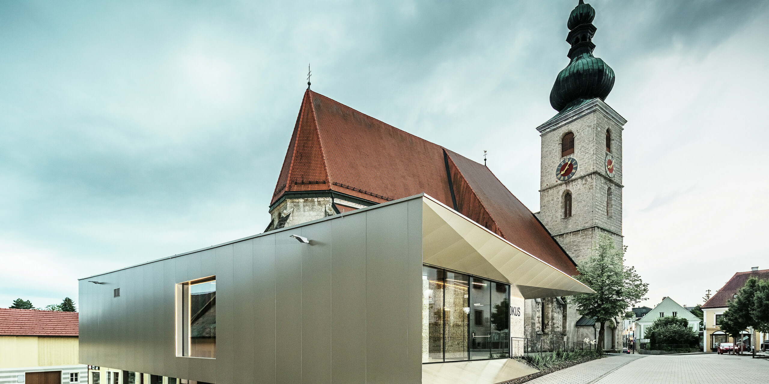 Die seitliche Ansicht zeigt den filigranen Dachüberstand, realisiert mit hochwertigen PREFA Aluminium Verbundplatten. Die exakte Verarbeitung ermöglicht eine moderne Optik mit klaren Linien und unterstreicht die architektonische Verbindung zwischen Alt und Neu.