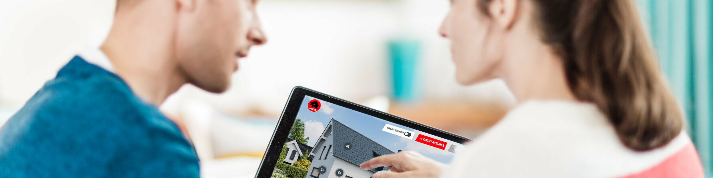 A couple sits together at a table looking at a tablet showing a digital representation of a house with a roof, façade and aluminium solar elements – in the context of the PREFA guide to roofs, façades and solar for home construction and renovation.