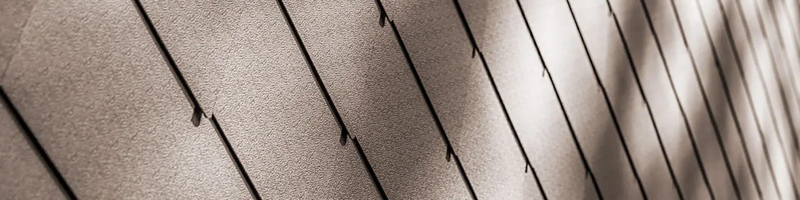The façade of the holiday home  with its nut brown rhomboid façade tiles 44 × 44 up close.