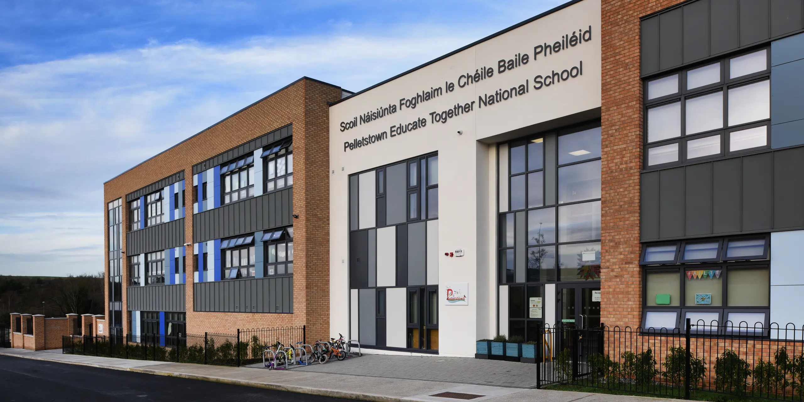 Close-up of the main entrance to Pelletstown Educate Together National School in Dublin. The aluminium façade made of PREFALZ standing seam P.10 light grey in combination with plaster and brick creates a unique appearance and provides the school with a durable and aesthetic building envelope.